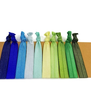 May include: A set of ten colorful hair ties in shades of blue, green, and yellow. The hair ties are arranged in a gradient from dark blue to dark green. They are made of a soft, stretchy material and are perfect for holding back hair.