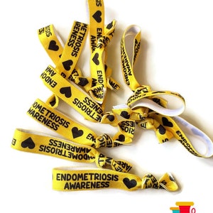 May include: Yellow elastic hair ties with black text that reads "Endometriosis Awareness" and a black heart.