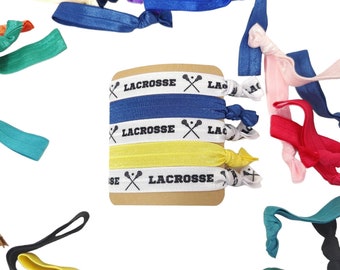 May include: A set of colorful hair ties with a lacrosse stick and "Lacrosse" printed on them. The hair ties are arranged around a card with the same lacrosse stick and text design.