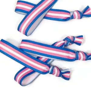 May include: Four blue and pink striped hair ties with knots at the ends. The hair ties are made of elastic material and are suitable for holding hair in place.