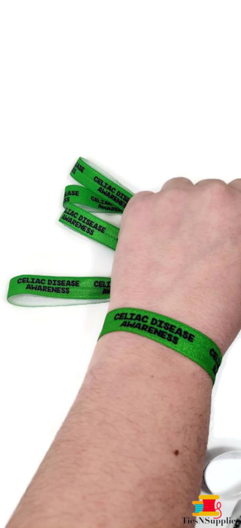May include: Green wristbands with the text "Celiac Disease Awareness" printed on them. The wristbands are worn on a person's wrist.