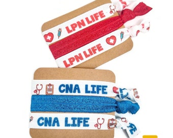 May include: Two sets of hair ties with white elastic and colorful printed designs. One set has red elastic with the text "LPN LIFE" printed in white. The other set has blue elastic with the text "CNA LIFE" printed in white.