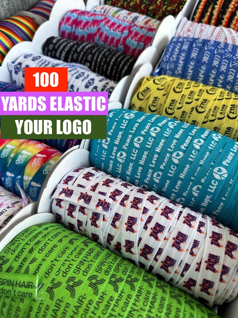 May include: A close-up of spools of elastic with various colorful and patterned designs. The spools are labeled with the text "100 YARDS ELASTIC YOUR LOGO".