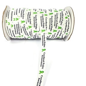 May include: A roll of white ribbon printed with the words "Cerebral Palsy Awareness" in black and green. The ribbon features green awareness ribbons. The roll is on a white background.