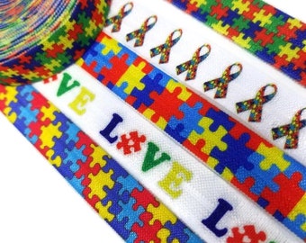 Może przedstawiać: Cztery kolorowe gumki do włosów z wzorem puzzli i napisami "I Love" powtarzającymi się na dwóch z nich. Gumki są białe z niebieskimi, czerwonymi, żółtymi i zielonymi puzzlami.