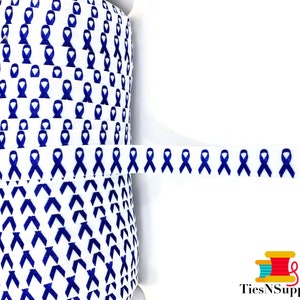 May include: A roll of white elastic with a repeating pattern of blue ribbon designs. The elastic is approximately 1 inch wide.