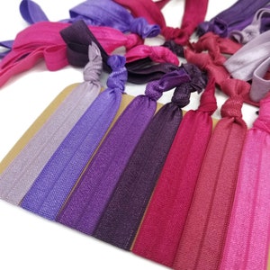 May include: A set of 10 colorful hair ties in shades of purple, pink, and red. The hair ties are made of a soft, stretchy material and are perfect for holding back hair.