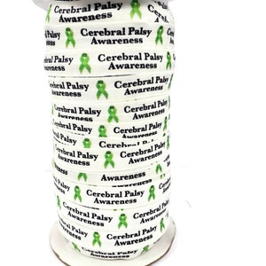 May include: A spool of white ribbon printed with "Cerebral Palsy Awareness" in black text and a green awareness ribbon graphic. The ribbon is tightly wound on a cardboard spool, ready for use in crafts or awareness campaigns.