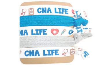 May include: Set of four white elastic hair ties with blue text that reads "CNA LIFE" and medical icons. Two of the hair ties have a silver glitter finish.