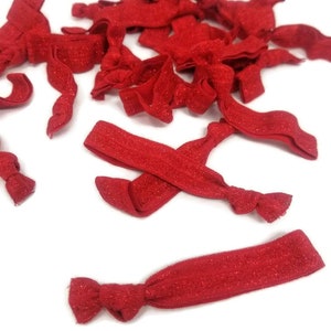 May include: A pile of red glitter hair ties. The hair ties are made of elastic and have a sparkly finish.