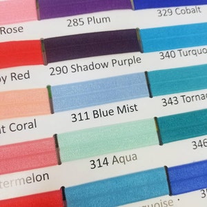 May include: A color chart with swatches of different shades of blue, purple, red, and pink. The swatches are labeled with numbers and names, such as "285 Plum", "311 Blue Mist", and "340 Turquoise".