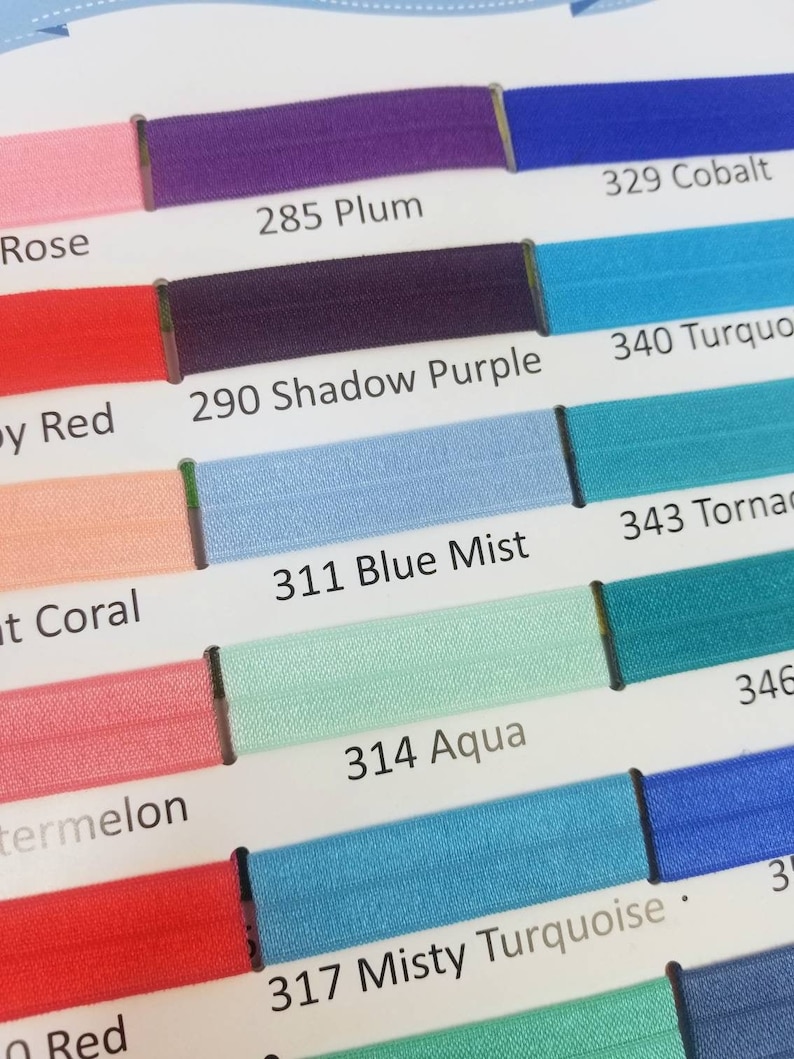 May include: A color chart with swatches of different shades of blue, purple, red, and pink. The swatches are labeled with numbers and names, such as "285 Plum", "311 Blue Mist", and "340 Turquoise".