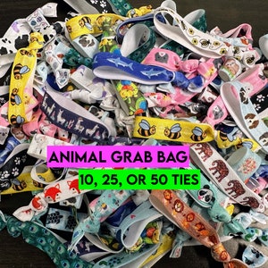 May include: A colorful assortment of elastic hair ties with various animal prints, including llamas, bees, pandas, and foxes. The text "ANIMAL GRAB BAG 10, 25, OR 50 TIES" is displayed on a pink banner.