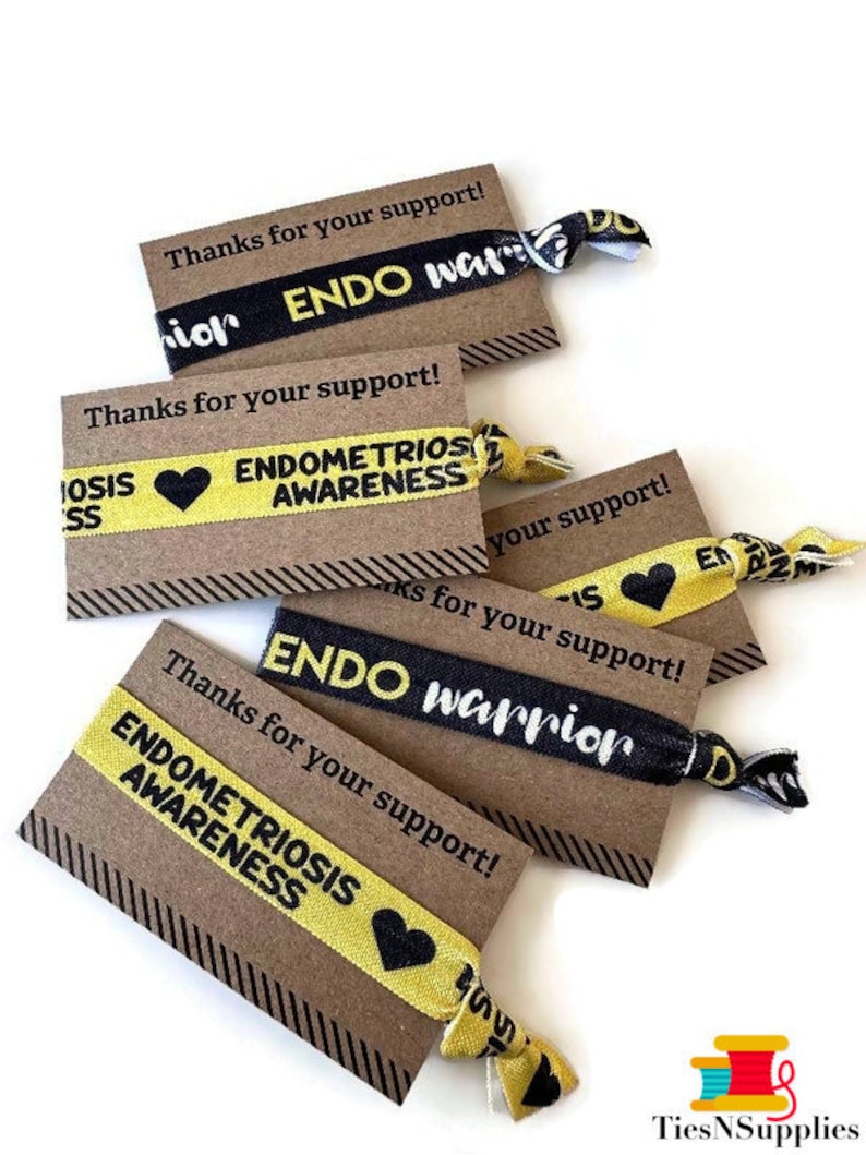 May include: Five brown cards with black and white striped borders and the text "Thanks for your support!" printed on them. Each card has a yellow and black elastic hair tie with the text "ENDO warrior" or "ENDOMETRIOSIS AWARENESS" printed on it.