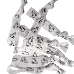 May include: A set of white elastic hair ties with a black ice skate print. The hair ties are made of a soft, stretchy material and are ideal for keeping hair out of the way.