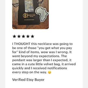 May include: A black drawstring pouch featuring the gold ROHO WEAR logo and website printed on the front. Inside the pouch is a clear plastic bag containing a gold-toned necklace with an Africa-shaped pendant. A matching Africa-shaped sticker is included.