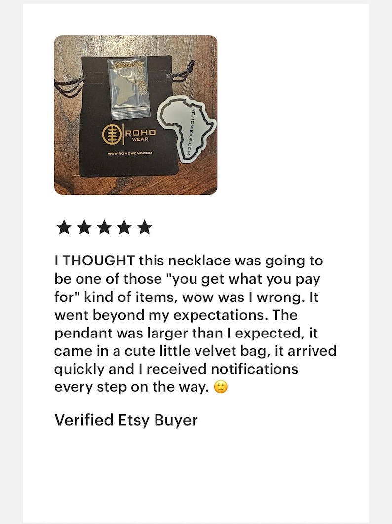May include: A black drawstring pouch featuring the gold ROHO WEAR logo and website printed on the front. Inside the pouch is a clear plastic bag containing a gold-toned necklace with an Africa-shaped pendant. A matching Africa-shaped sticker is included.