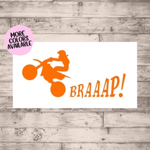 May include: Orange silhouette of a motocross rider performing a wheelie on a dirt bike with the word "BRAAAP!" in orange text.