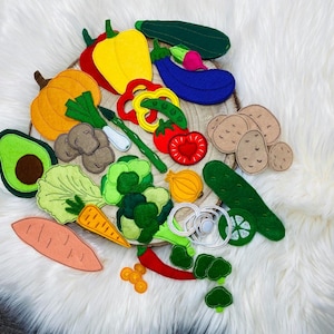 May include: A collection of felt food items, including a green avocado, a red tomato, a yellow onion, a green cucumber, a green broccoli, a red pepper, a yellow pepper, a green courgette, a purple aubergine, a brown potato, a green lettuce, a carrot, a red chilli pepper, and a brown sweet potato.
