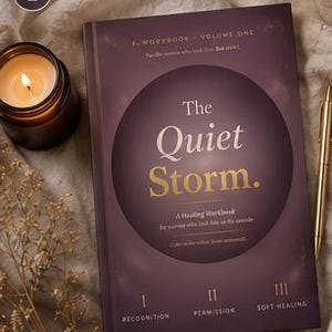 Puede incluir: Un libro de color púrpura oscuro titulado The Quiet Storm, A Healing Workbook, con un gran círculo central y tres secciones etiquetadas como I Recognition, II Permission y III Soft Healing. Una vela encendida en un frasco marrón y un bolígrafo dorado.