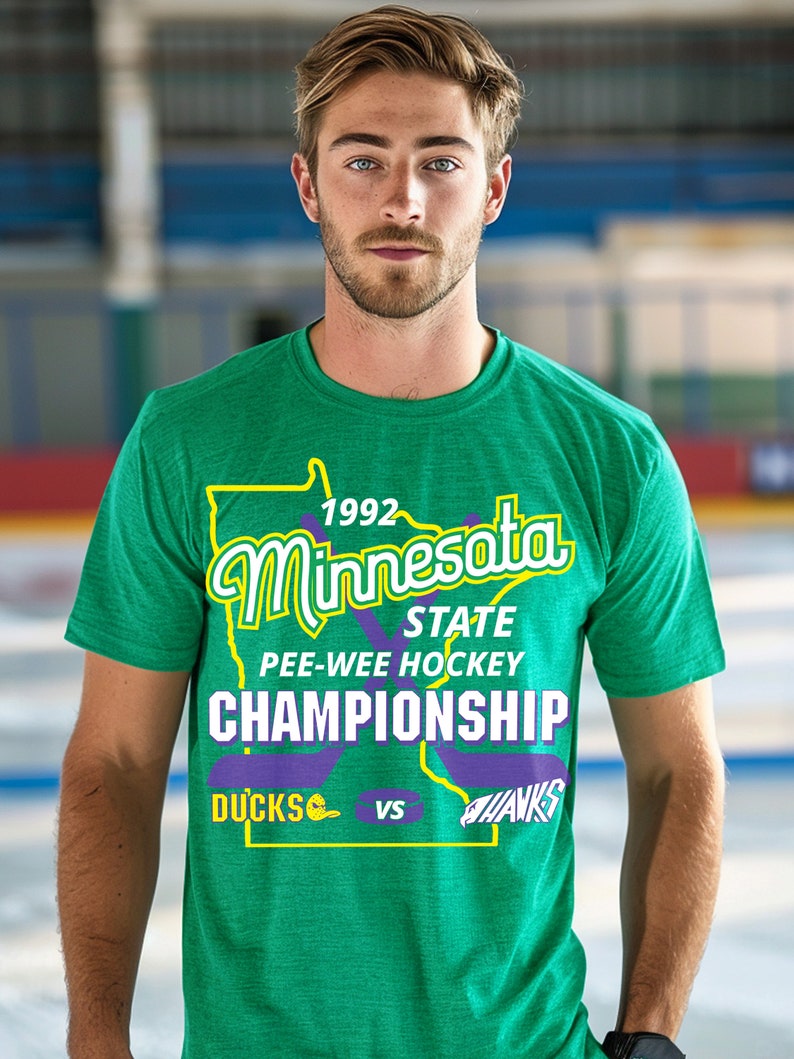 May include: A green t-shirt with a purple outline of the state of Minnesota. The text "1992 Minnesota State Pee-Wee Hockey Championship Ducks vs Hawks" is printed on the shirt.