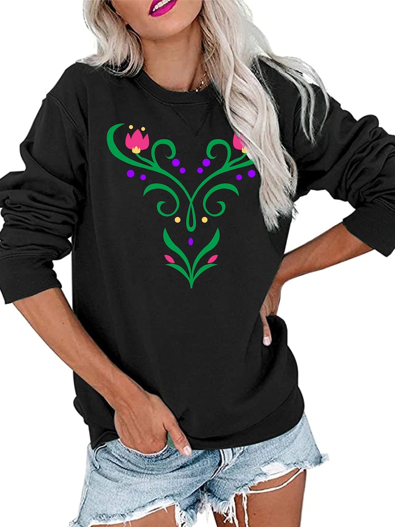Op de afbeelding: Zwart longsleeve sweatshirt met een groen, paars en roze bloemenontwerp op de voorkant.