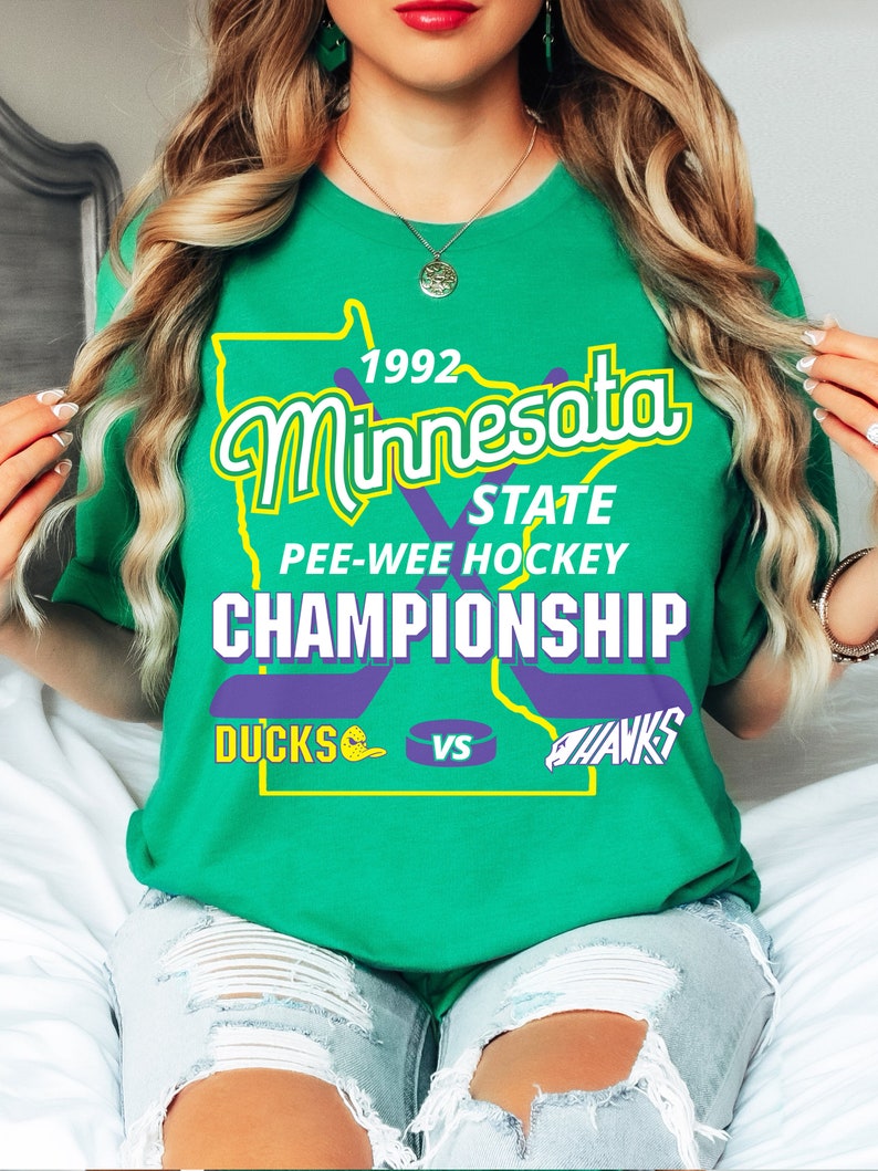 May include: Green t-shirt with a graphic of the state of Minnesota, the text "1992 Minnesota State Pee-Wee Hockey Championship", and the words "Ducks" and "Hawks" with hockey stick graphics.