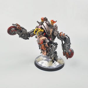 May include: A painted miniature figure of a mechanical walker suit with metallic silver plating and two large circular saw blades on its arms. A humanoid figure with pale skin and yellow horns is integrated into the centre of the machine.