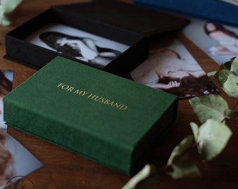 May include: A green velvet box with gold lettering that reads "FOR MY HUSBAND". The box is closed and sitting on a wooden surface.