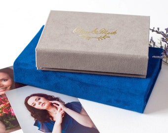 May include: Two velvet boxes, one gray and one blue, stacked on top of each other. The top box has the text "Olivia & Mark" in gold lettering.
