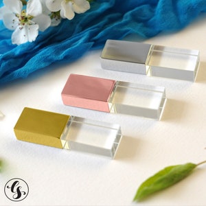 May include: Four USB flash drives with clear crystal cases and different colored metal caps. The caps are silver, rose gold, gold, and black.