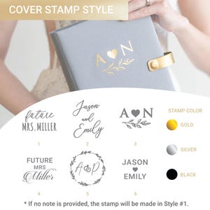 May include: A light gray photo album with a gold foil stamp featuring the letters A and N separated by a heart and a leaf sprig. The image displays six customizable stamp styles and three color options: gold, silver, and black foil.