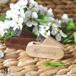 Puede incluir: Dos memorias USB de madera con la palabra "Memories" grabada en ellas. Las memorias est&aacute;n cerradas y se encuentran sobre una superficie de mimbre tejido.