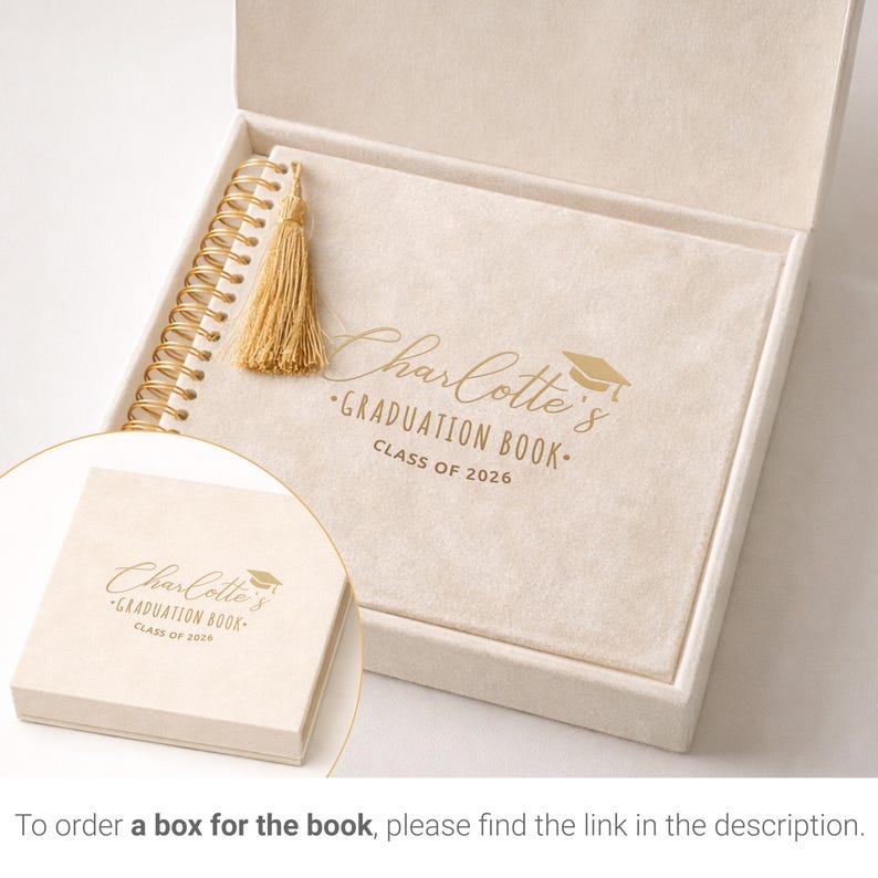 May include: A graduation book in a cream-colored box. The book has a gold spiral binding and a gold tassel. The cover reads "Charlotte's Graduation Book Class of 2026" in gold lettering. A smaller box with the same text is in the foreground.
