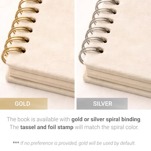 May include: Close-up of a cream-colored notebook with a gold spiral binding. The notebook has a soft, textured cover. The text "GOLD" is below the notebook. The text "SILVER" is below a similar notebook with a silver spiral binding.
