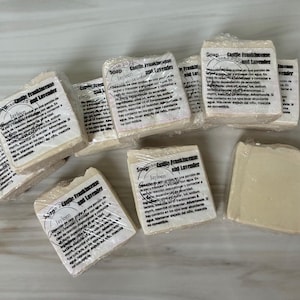 Puede incluir: Varias pastillas de jabón envueltas en plástico transparente están dispuestas sobre una superficie clara. Cada pastilla tiene una etiqueta blanca con texto, incluyendo "Soap Castile Frankincense and Lavender" y la marca "Jayleen".