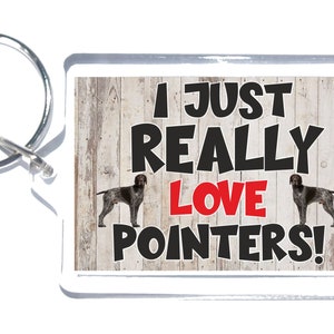 May include: A white and brown wooden background with two German Shorthaired Pointer dogs on either side of the text "I Just Really Love Pointers!" The text "Love" is in red. The image is on a white acrylic keychain.
