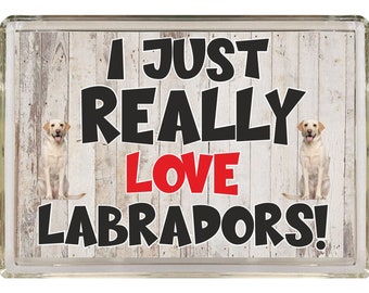 Könnte beinhalten: Ein weißes Holzschild mit dem Text "I just really love Labradors!" in schwarzen und roten Buchstaben. Zwei gelbe Labrador Retriever Hunde sind auf beiden Seiten des Textes abgebildet.