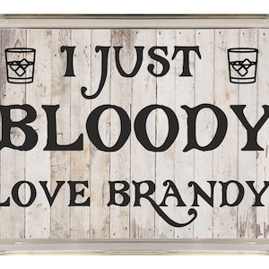 May include: A white wooden sign with black text that reads "I just bloody love brandy!" with a glass of brandy on each side of the text.