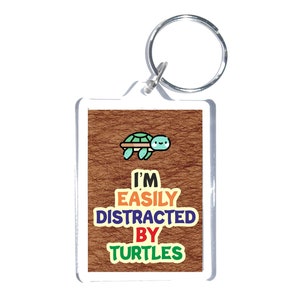 May include: A brown and white key chain with a cartoon turtle and the text "I'm easily distracted by turtles".