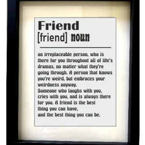 Op de afbeelding: Een zwart-wit ingelijste print met het woord "Friend" in vetgedrukte letters, gevolgd door de definitie van het woord in een kleiner lettertype. De definitie luidt: "Een onvervangbare persoon, die er voor je is door alle ups en downs van het leven, ongeacht wat je meemaakt. Een persoon die weet dat je raar bent, maar je raarheid omarmt. Iemand die met je lacht, met je huilt en er altijd voor je is. Een vriend is het beste wat je kunt hebben, en het beste wat je kunt zijn."