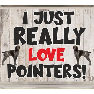 Op de afbeelding: Een wit houten bord met de tekst "I just really love pointers!" in zwarte letters. Twee Duitse Kortharige Wijzers staan afgebeeld aan weerszijden van de tekst. Het woord "love" is rood.