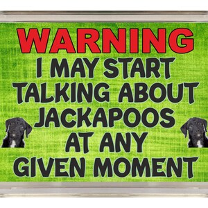 Puede incluir: Un cartel de advertencia verde y blanco con texto negro que dice "ADVERTENCIA PUEDO EMPEZAR A HABLAR DE JACKAPOOS EN CUALQUIER MOMENTO". Dos perros negros aparecen a cada lado del texto.