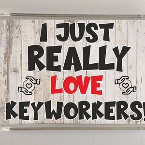 May include: A white woodgrain background with black text that reads "I just really love keyworkers!" with two red hearts and black hands on either side of the word "love".