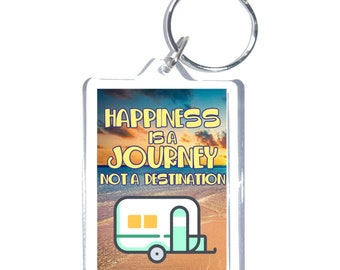 May include: A white acrylic keychain with a sunset background and the text "Happiness is a Journey Not a Destination". A cartoon camper van is in the bottom of the image.