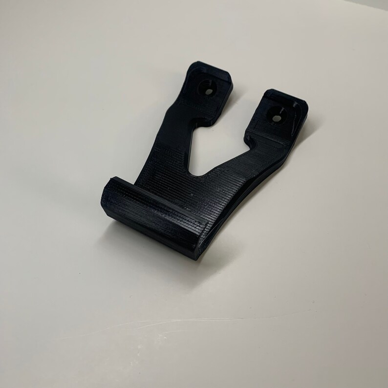 Puede incluir: Un soporte de pared de pl&aacute;stico negro impreso en 3D con dos agujeros para montaje.
