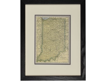 May include: A framed vintage map of Indiana, showing the state's roads and towns. The map is printed on aged paper, set within a cream-coloured mount, and enclosed in a black wooden frame. The word "INDIANA" is printed at the bottom.