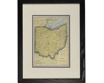 May include: Framed vintage map of Ohio, featuring a detailed depiction of the state's roads, cities, and geographical features. The map is in a black frame with a cream-colored matting, enhancing the antique aesthetic. The map is a historical piece.