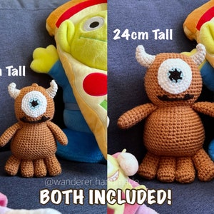 May include: Two crocheted brown one-eyed monsters with horns. The smaller monster is 15 cm tall and the larger monster is 24 cm tall. Both monsters have a white eye and a black mouth. The text "BOTH INCLUDED!" is at the bottom of the image.
