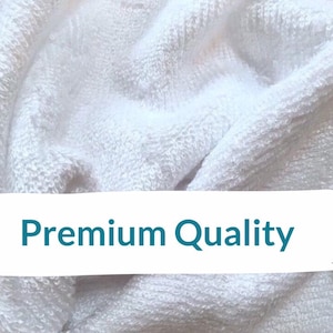 May include: Close-up of a white, textured fabric with the words "Premium Quality" in teal. The fabric appears to be soft and plush, possibly a towel or blanket. The image highlights the quality of the material.